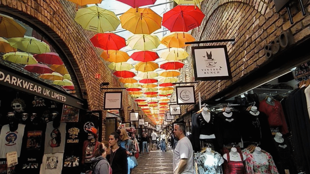"Gli Inglesi Sono Freddi e Distaccati" (Falso Mito) Ombrelli colorati appesi al Camden Market Londra con folla di visitatori - mercato iconico