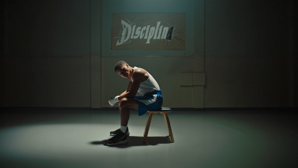 Giovane atleta seduto solo in palestra con cartello 'Disciplina' danneggiato - burnout da produttività nello sport