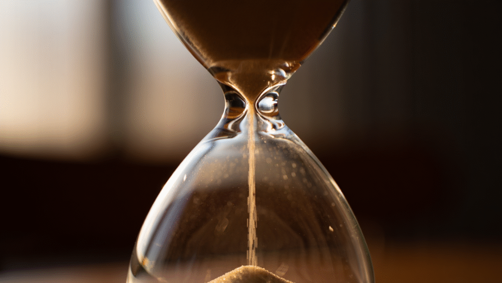 Minimalismo del Tempo: Sottrarre per Moltiplicare Clessidra con sabbia dorata che scorre lentamente, metafora della lentezza consapevole e del tempo vissuto con presenza mentale
