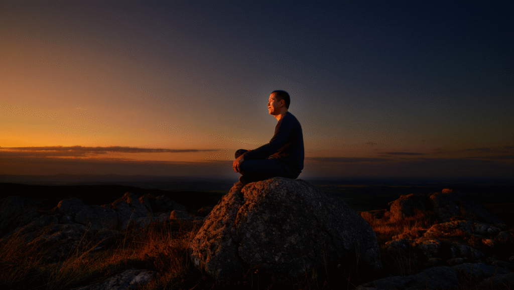 Uomo in meditazione su roccia al tramonto accettazione e resilienza principi stoici per serenità interiore
