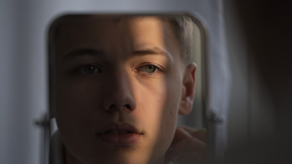 Riconoscere Chi Ti Eleva (e Chi Ti Trascina Giù) Giovane ragazzo che riflette davanti allo specchio durante percorso di crescita personale e introspezione