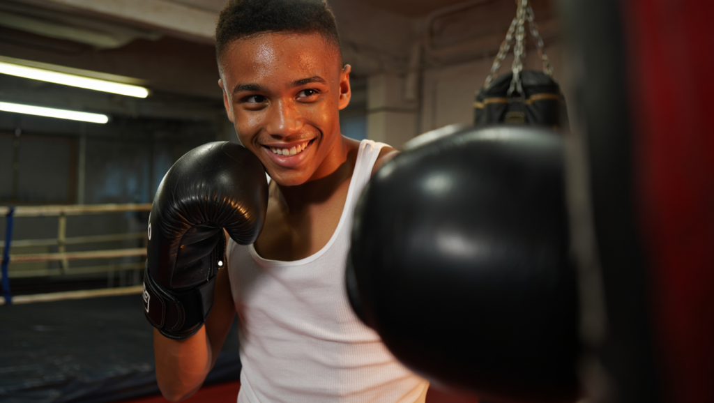 1. Ama Quello Che Fai (O Sarai Sempre Un Passo Indietro) Giovane pugile sorridente in palestra dopo allenamento: resilienza sportiva e mentalità da campione nel combattimento