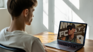 Giovane atleta guarda intervista Conor McGregor su laptop per apprendere mindset vincente e disciplina mentale